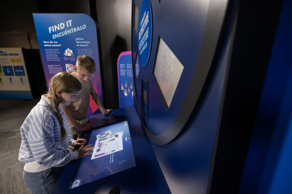 Visitors become “cancer detectives” in a hunt to unmask or rule out hidden cancers. Would-be sleuths apply screening and evaluation tools to different tissues. The interactive highlights the importance of routine screenings and paying attention to unusual symptoms. (Photo: The Journey to End Cancer)
